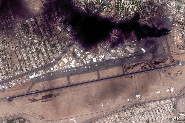 This satellite image provided by Maxar Technologies shows smoke rising from two burning planes at Khartoum International…